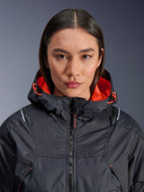 Alpinestars Molly Air Jacket, Women's Motorcycle Jacket, Black and Fluo Coral, close-up front view on a model, ripstop textile with laser-perforated ventilation, bright orange mesh hood lining and drawstrings, featuring Nucleon Flex Plus armor branding