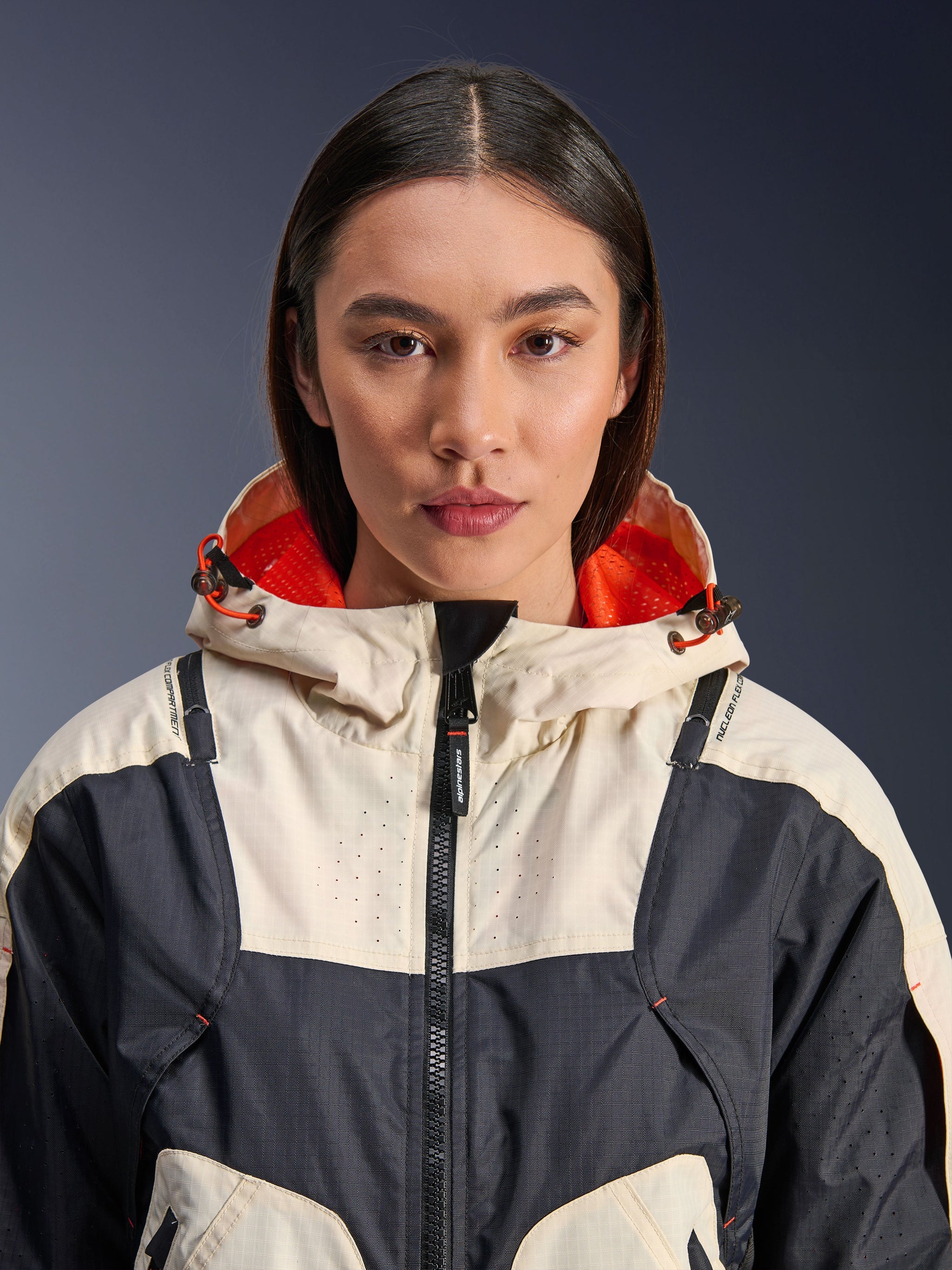 Alpinestars Molly Air Jacket, Women's Textile Motorcycle Jacket, Black Almond, close-up front view of a model wearing the jacket with a cream and black paneled design, bright orange mesh-lined hood, and laser-perforated detailing on the chest