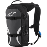 Alpinestars Iguana Hydration Backpack, Off-Road Hydration Pack, Black Anthracite and White, featuring padded mesh shoulder straps, front compression straps with buckles, zippered compartments, and a blue hydration tube with nozzle