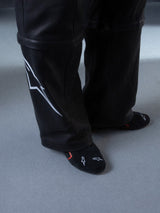 Alpinestars RSRV Starline Shoes, Black premium sneakers with white logo detailing, shown with black socks featuring red and white accents, lifestyle shot on light gray floor