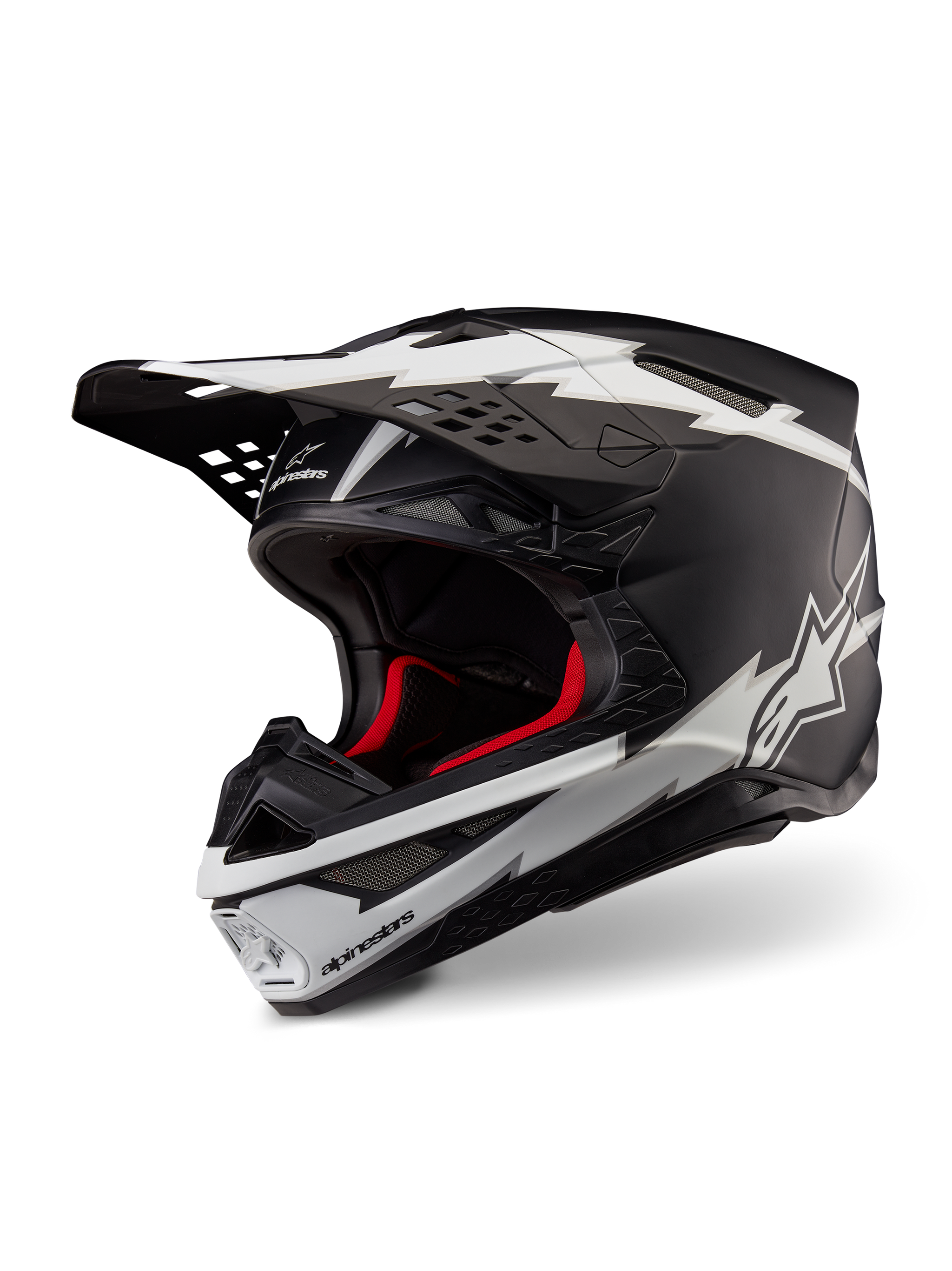 Alpinestars Supertech M10 Ampress Helmet, Motocross Helmet, Matte Black and White, featuring bold white lightning-style graphics and star logos, red internal lining, multi-composite carbon shell with a streamlined aerodynamic profile