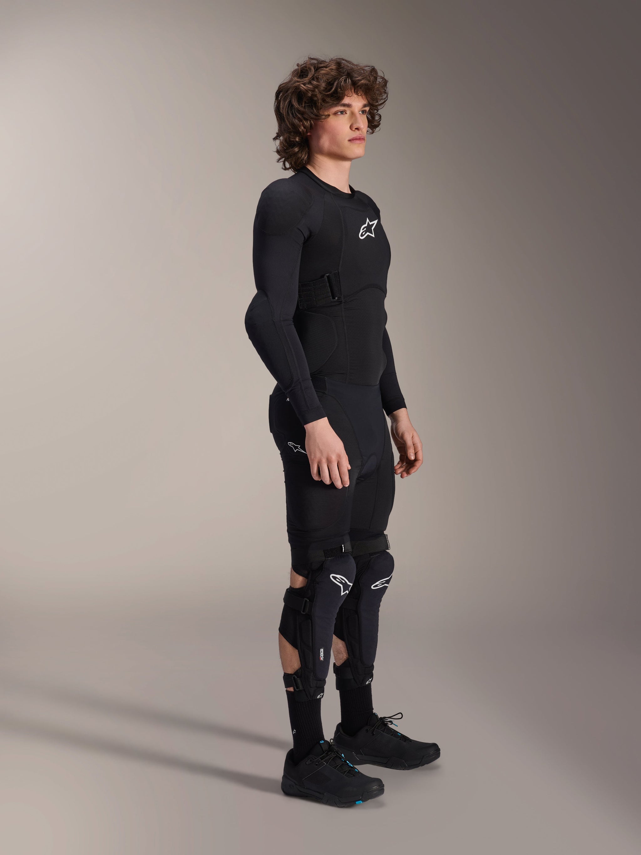 Alpinestars A-Impact Plasma Protection Jacket - Long Sleeve, Black, worn by a model with matching protective gear including knee guards and shorts, featuring white Astars logos, breathable mesh construction, and streamlined design for off-road cycling.
