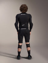 Alpinestars A-Impact Plasma Protection Jacket - Long Sleeve, back view, black with white Alpinestars logos, worn with protective shorts and knee guards for full-body mountain bike protection