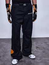 RSRV Arena Suit Pants, Black Racing Pants with McLaren and Alpinestars Logos, Orange Side Patches, Premium Motorsport Apparel, Worn with Black and Orange Gloves and White Racing Shoes