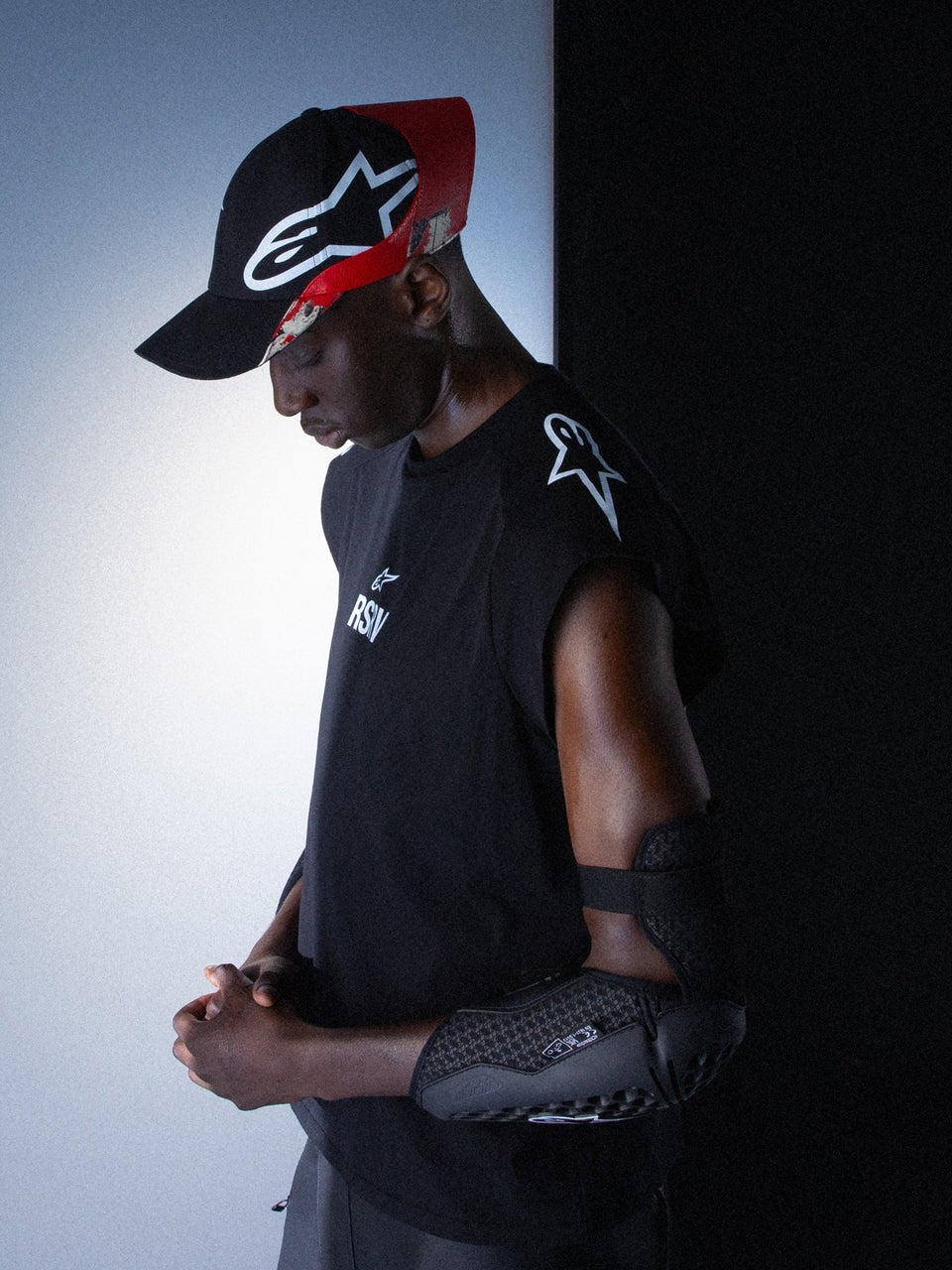 RSRV Tech Tank, Black Sleeveless Performance Shirt, Unisex, Black and White, Premium Technical Fabric, Worn with Black Elbow Protection and Cap, Motorsport-Inspired Lifestyle Wear