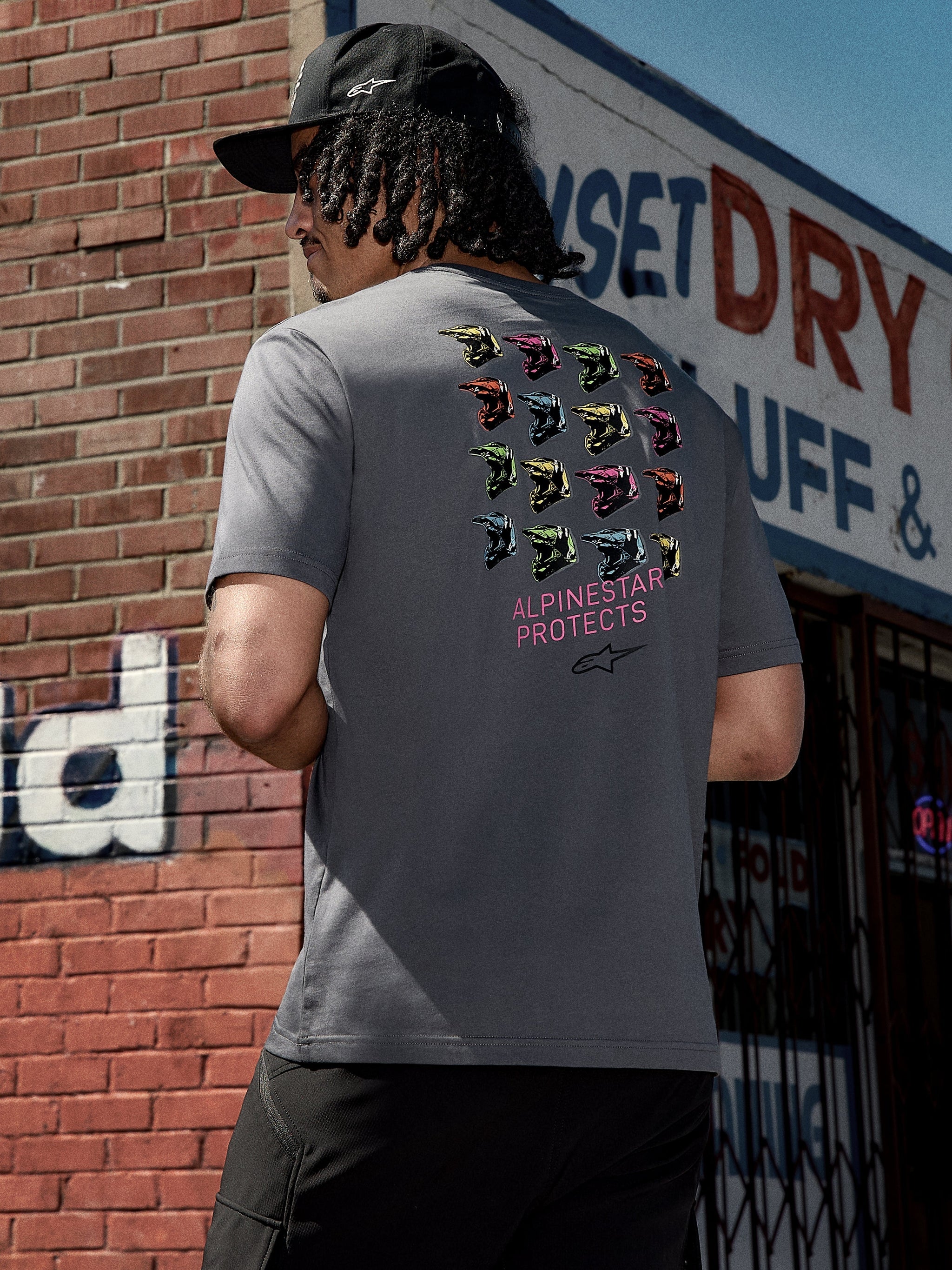 Alpinestars Pop Helmet CSF Tee, Short Sleeve T-Shirt, Charcoal Gray, back graphic featuring colorful M10 helmets and pink "ALPINESTAR PROTECTS" text, casual motorsport-inspired streetwear