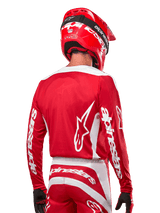 Motocross rider wearing Alpinestars 2024 Fluid Lurv Jersey, Mars Red and White, rear view showing white Alpinestars logo on back and branding on sleeves, paired with a matching red helmet and black gloves, professional off-road racing gear