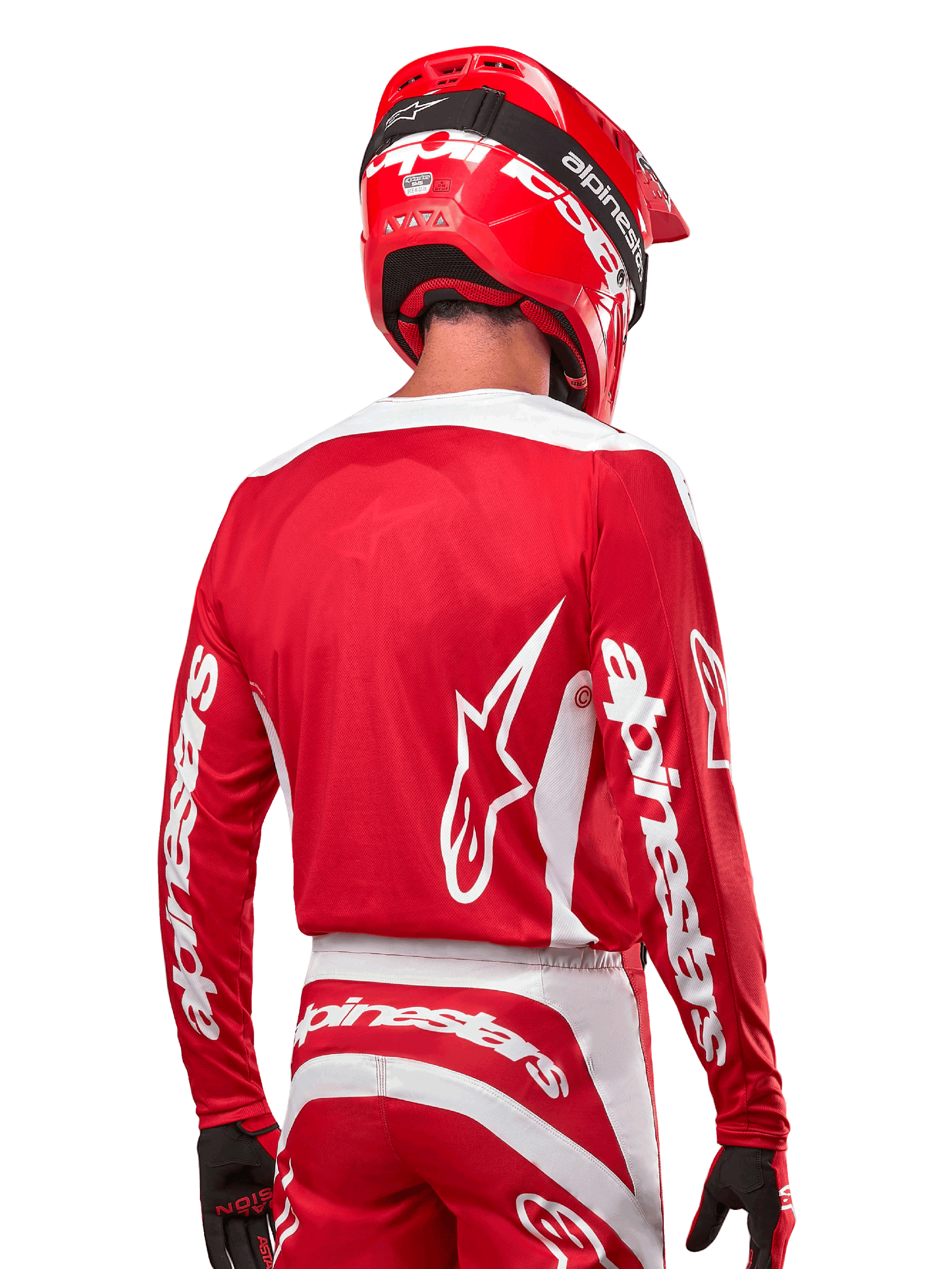 Motocross rider wearing Alpinestars 2024 Fluid Lurv Jersey, Mars Red and White, rear view showing white Alpinestars logo on back and branding on sleeves, paired with a matching red helmet and black gloves, professional off-road racing gear