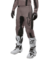 Alpinestars 2024 Fluid Lurv Pants, Motocross Pants, Mud Black and Black, featuring Alpinestars logo, worn with black gloves and white motocross boots, sporty design for off-road racing