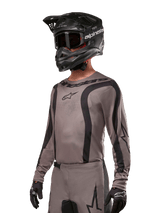 Alpinestars 2024 Fluid Lurv Jersey, Motocross Jersey, Mud Black and Gray, long-sleeve design with curved black stripes and logos, worn with matching pants and a black motocross helmet, coordinated off-road racing setup