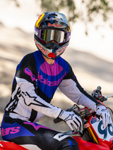 Motocross rider on a red dirt bike, Limited Edition HUNTA96 XXV Supertech Vision Goggles in purple and white with silver mirror lenses, matching purple black and white Alpinestars jersey and pants, Red Bull helmet, white gloves, coordinated professional motocross racing gear.