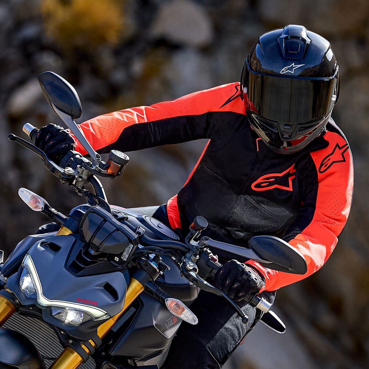 Alpinestars Viper Air V4 Jacket, Red Fluo and Black, worn by a motorcycle rider leaning into a turn on a sportbike, black full-face helmet and gloves, high-performance racing and sport riding gear