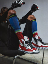 Alpinestars RSRV Legacy Shoe, Red White and Black High-Top Sneakers, Premium Lifestyle Footwear, Worn Texture with Black Scuffs, Person Wearing Colorful Striped Socks and Black Gloves