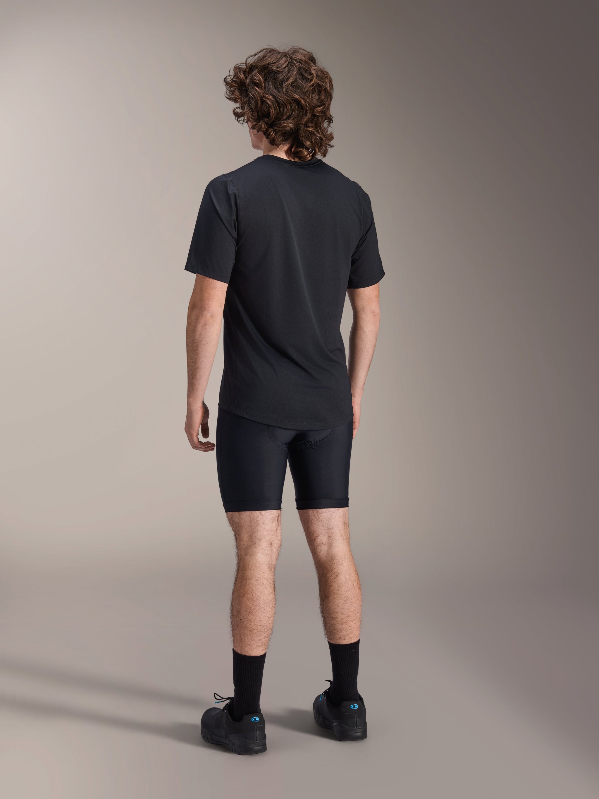 Alpinestars A-Dura Liner Shorts, Black Cycling Liner Shorts, back view on model, tight-fitting stretch fabric with visible chamois padding seams, paired with a black t-shirt and cycling shoes, mountain bike apparel