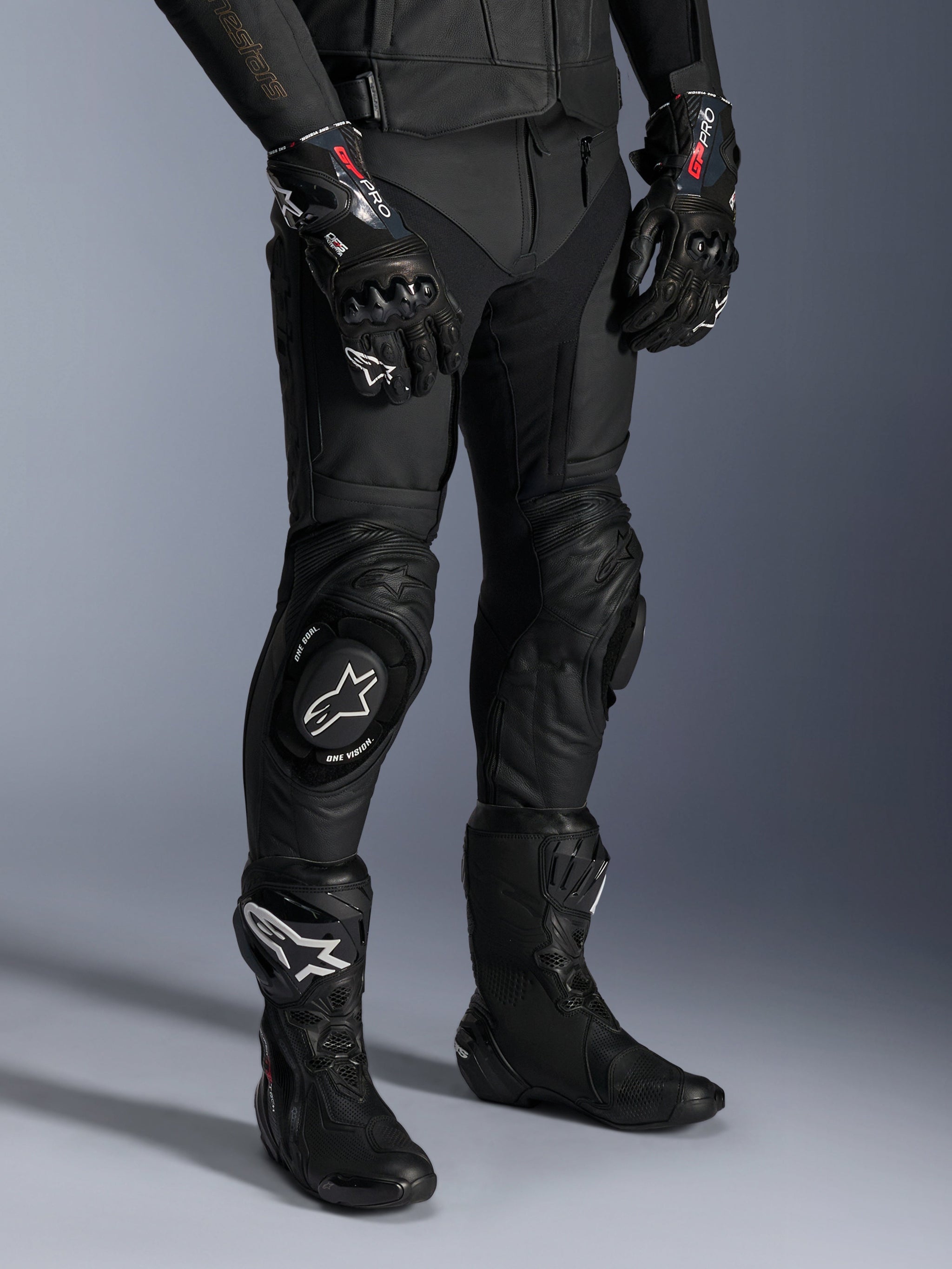 Missile V3 Leather Pants, Black Motorcycle Racing Pants, worn with matching GP Pro gloves and technical racing boots, premium leather construction with white logo knee sliders, professional racing aesthetic for track and road use